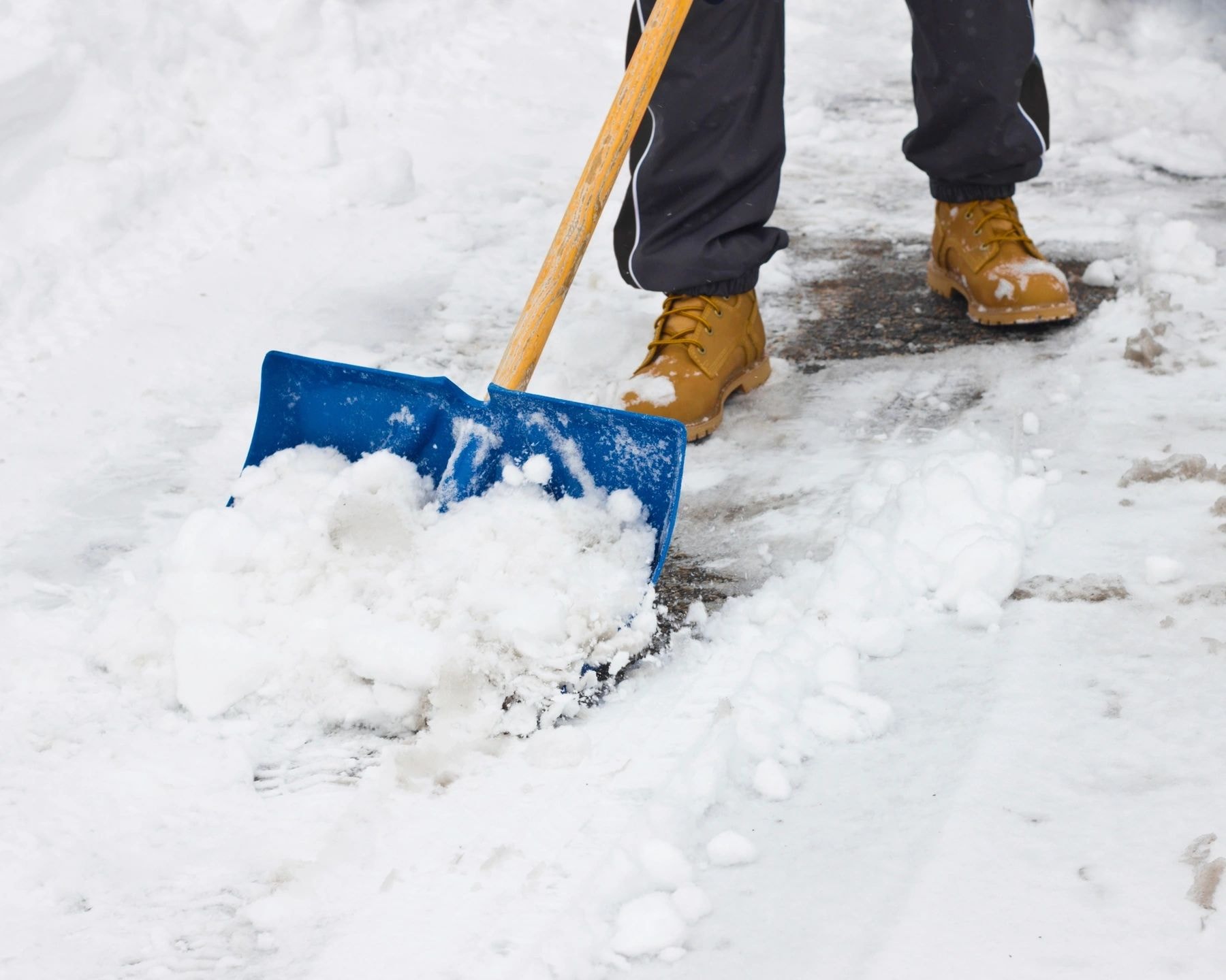 Crew member clearing accumulated snow from a pedestrian route
