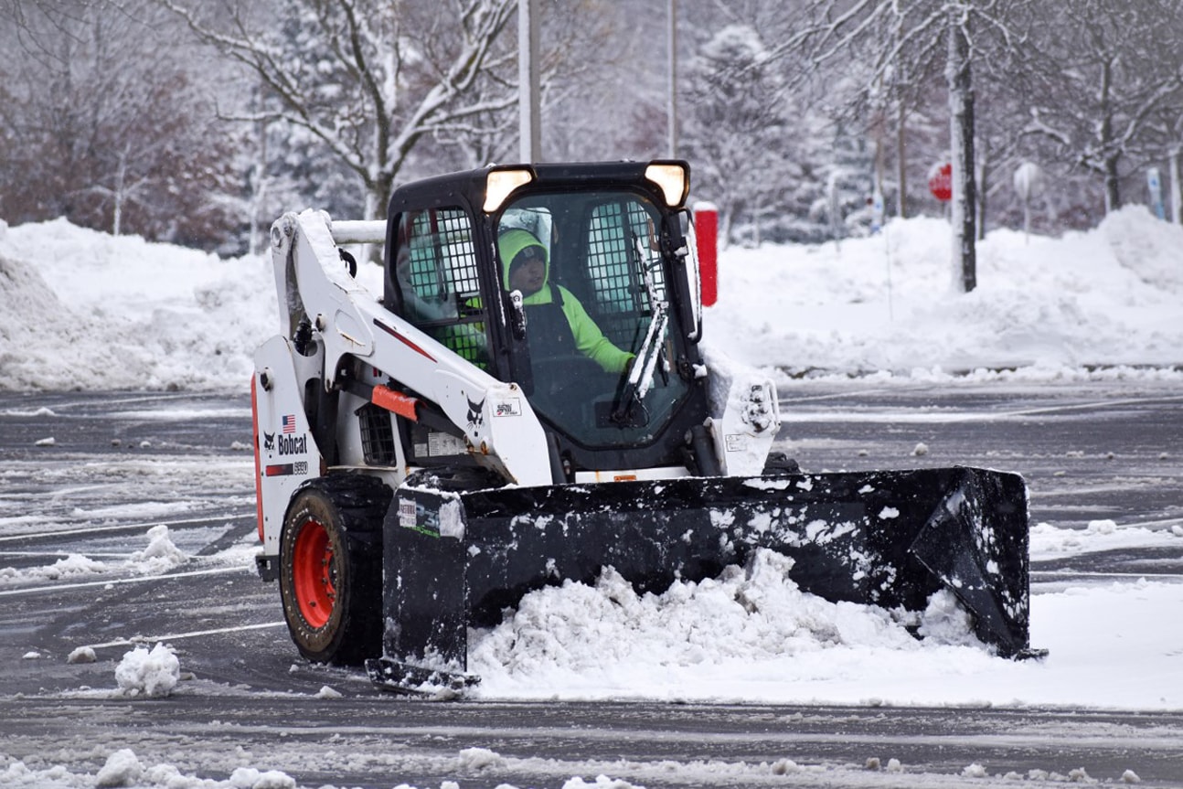 Commercial snow equipment actively clearing a parking lot